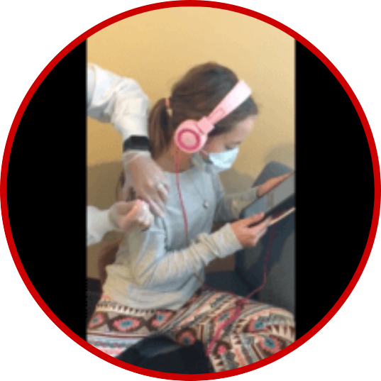 Woman wearing headphones and a mask using a tablet while receiving a vaccine shot.